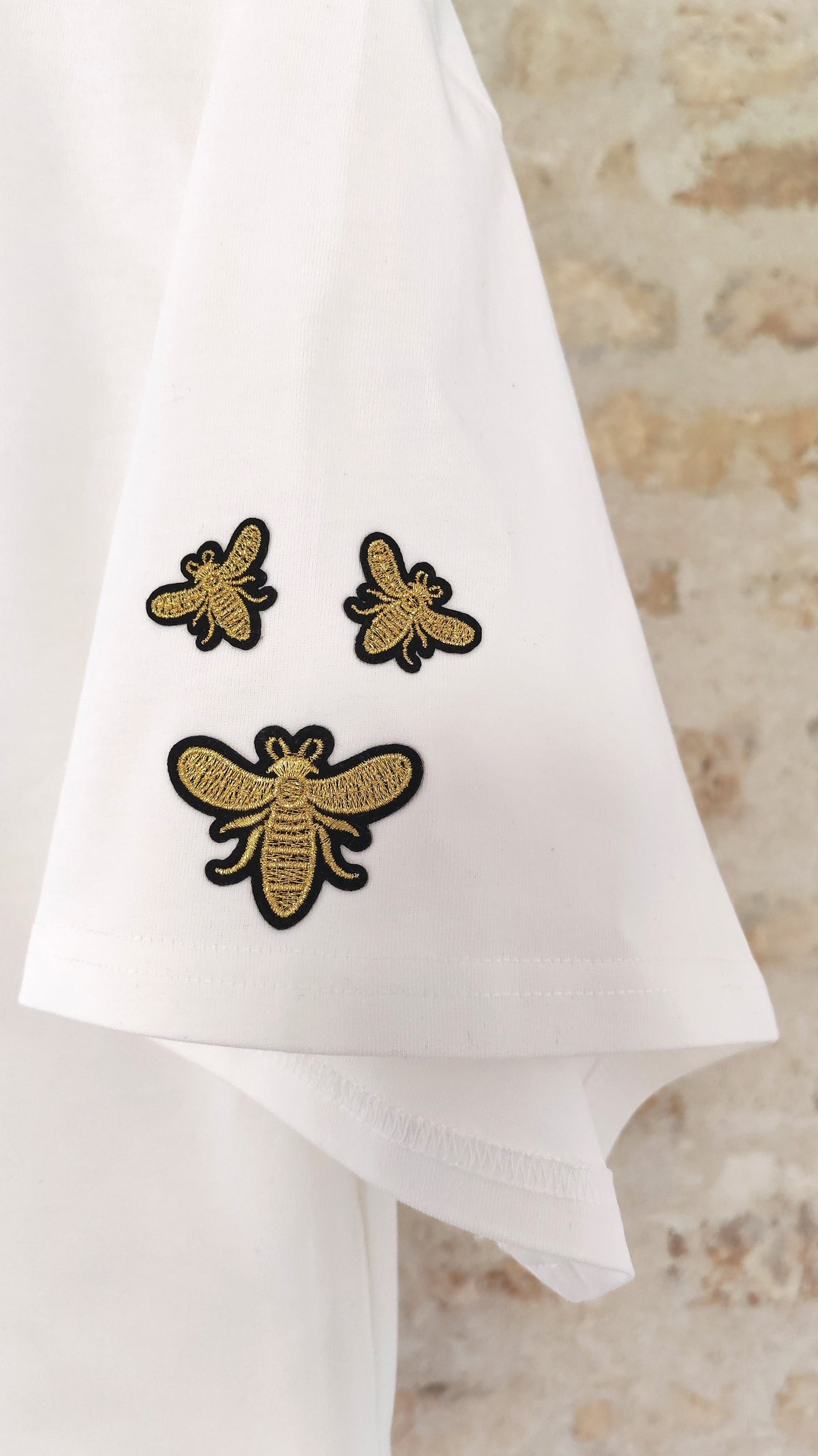 Détail écussons abeilles dorés brodés sur t-shirt blanc – BFunny